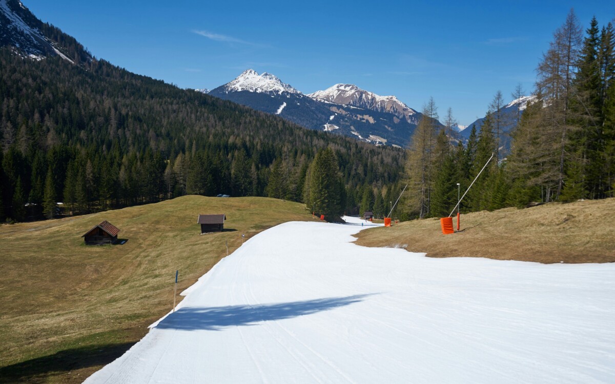 A ski slope made of artificial snow surrounded by green meadows.