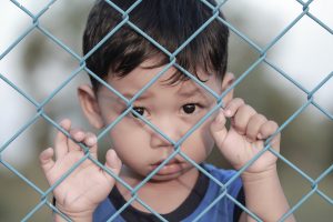 boy behind chain link fence