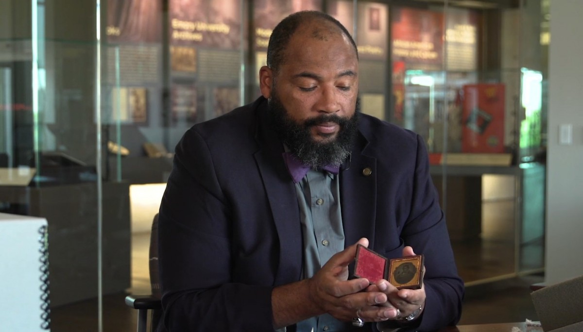 Pellom McDaniels III holds an antique daguerreotype from the 1830s