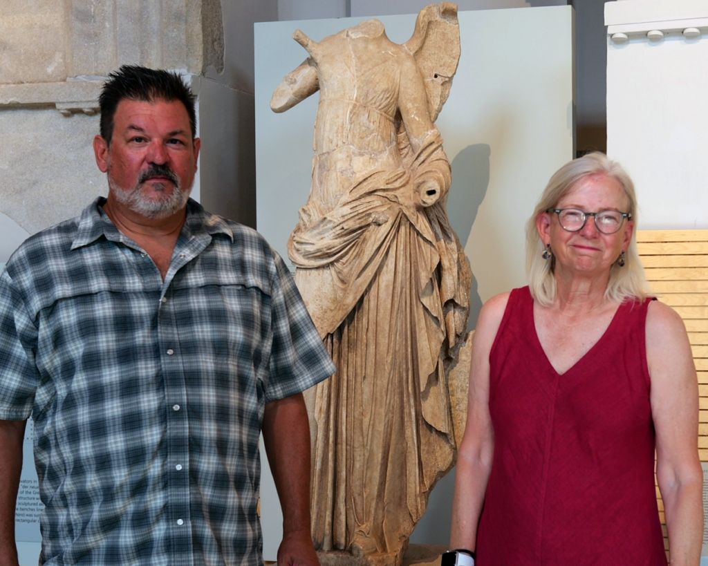 Michael Page (left) and Bonna Wescoat (right) posed in front of a replica of the Winged Victory of Samothrace statue inside the reopened Archaeology Museum of Samothrace