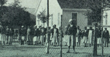 Part of the book cover of Kylie Smith's book Jim Crow in the Asylum. It depicts an old photograph of a group of Black women standing behind a fence infront of a mental health facility.