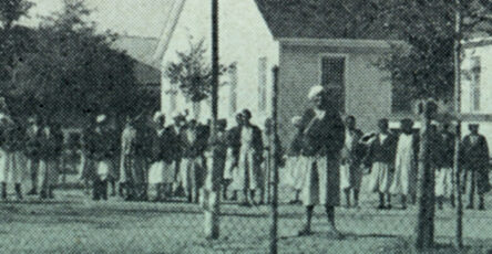 Part of the book cover of Kylie Smith's book Jim Crow in the Asylum. It depicts an old photograph of a group of Black women standing behind a fence infront of a mental health facility.