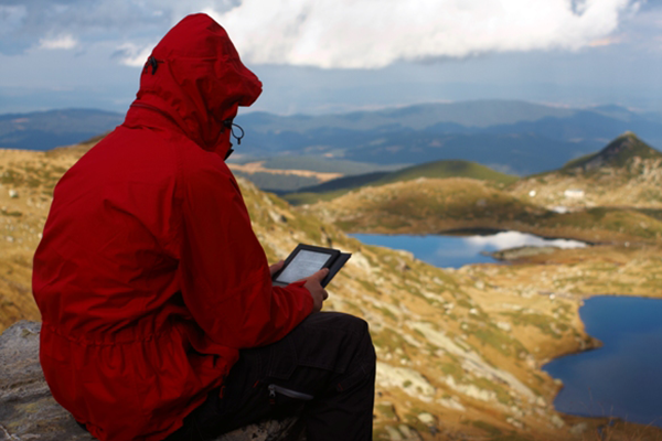 Photo of person sitting on a mountian with an iPad