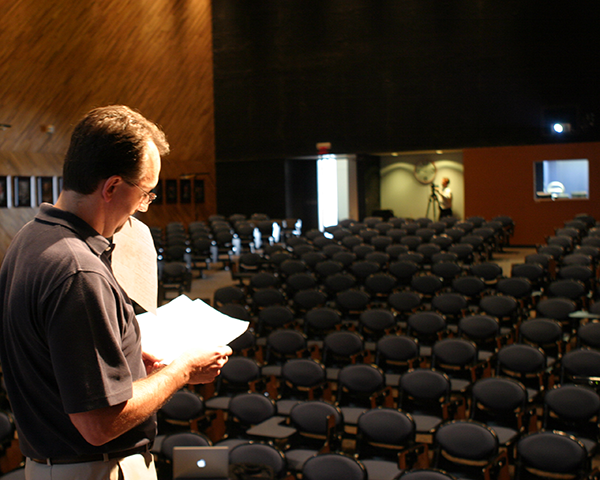 Photo of a man standing on the stage in an empty auditorium