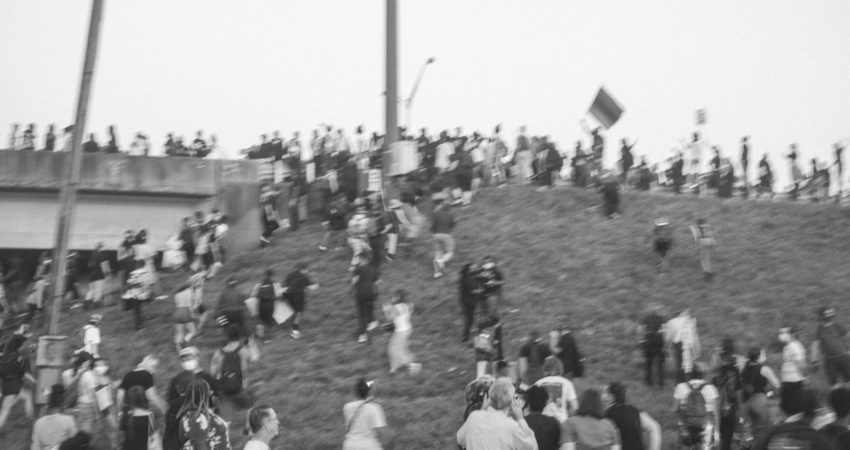 A black-and-white photo of around 70 people climbing up the grassy hill onto the interstate during the protests against the police killing of Rayshard Brooks
