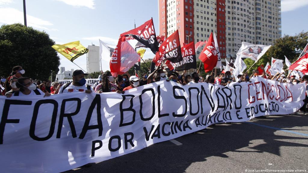 Foto de um protesto contra Bolsonaro. Os protetores tem uma banndeira que diz "Fora Bolsonaro Genocida, por vacina auxílio e educação"