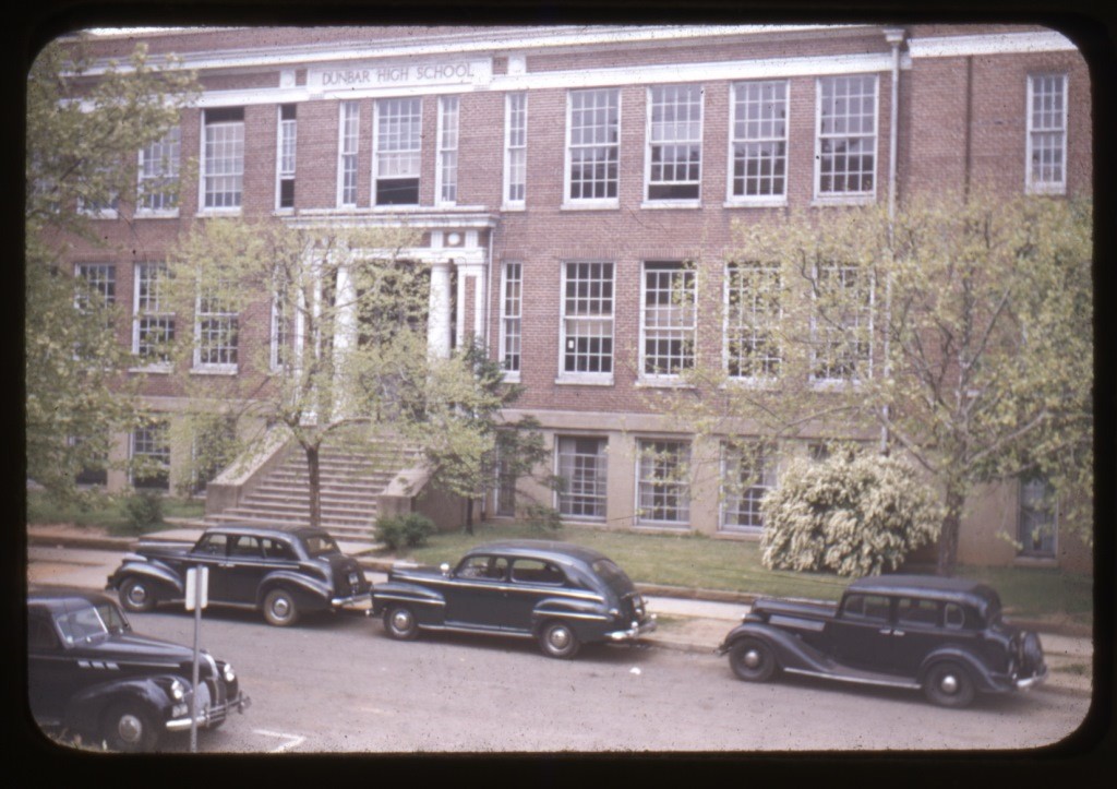 Large brick building with old cars parked out front. Dunbar High School.