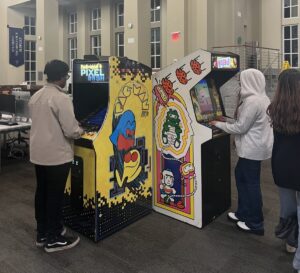 Two students at Game Night 2023 playing arcade games in the oxford college library 