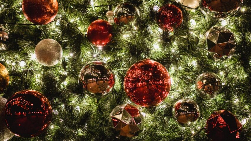 Close up photo of a Christmas tree with lights and red and gold ornaments