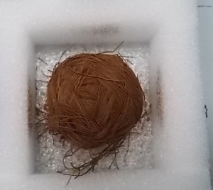 Ball of reddish brown finely spun cotton thread, some of which is breaking off due to its age.