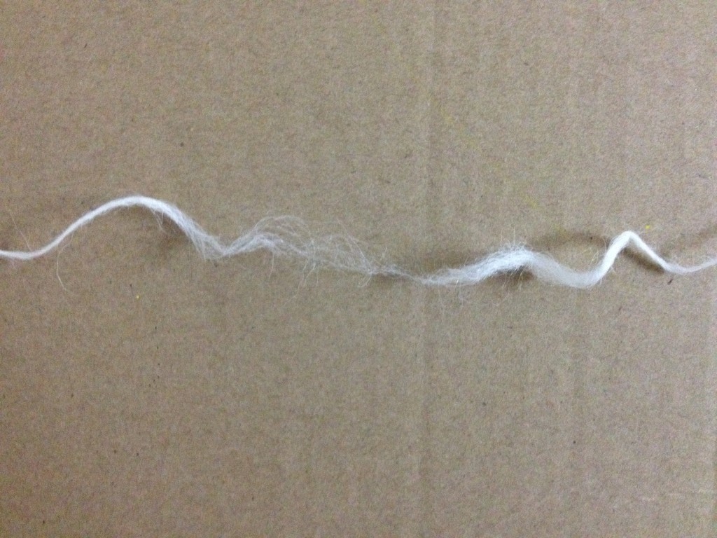Thick thread pulled apart into two halves. The two halves are still connected by some of the fiber but the fiber in the middle has lost its tension and turned back into a fuzz rather than being tightly grouped