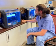 person in scrubs uniform watching 3D printing