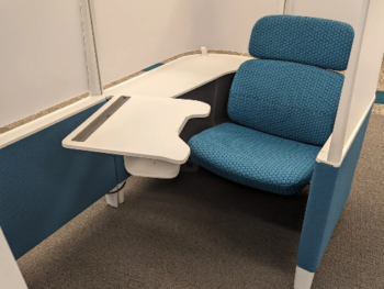 study pod seating. a blue chair with a white swing-arm desk and privacy dividers